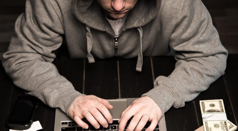 young-hacker-in-hoodie-sitting-at-table-and-using-2022-11-03-03-31-52-utc.jpg